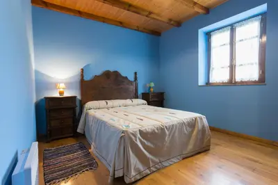 a bedroom with blue walls and a bed and a window at Casa Aniceto in Taramundi