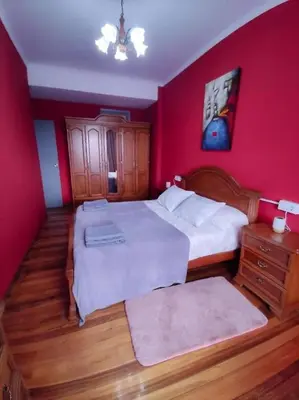 a bedroom with two beds and a red wall at Vivienda Turística Mou in Arzúa