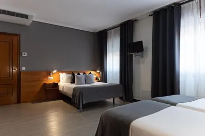 a hotel room with two beds and a television at Hotel & Spa Carlos desde 1996 in Melide