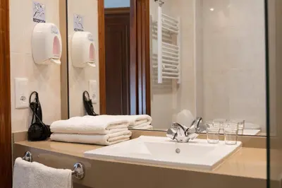 a bathroom with a sink and a mirror at Hotel & Spa Carlos desde 1996 in Melide