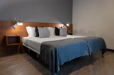 a bedroom with a large bed with a blue blanket on it at Hotel & Spa Carlos desde 1996 in Melide