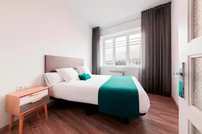 a hotel room with a large bed and a window at Lux Apartamentos Santiago in Santiago de Compostela