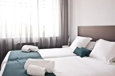 a bedroom with two beds with white sheets and pillows at Lux Apartamentos Santiago in Santiago de Compostela