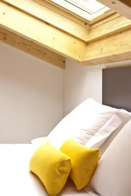 a white bed with two yellow pillows on it at Lux Apartamentos Santiago in Santiago de Compostela