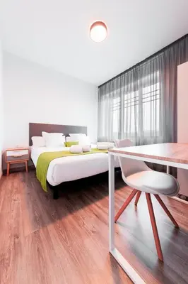 a bedroom with a large bed and a table and chair at Lux Apartamentos Santiago in Santiago de Compostela