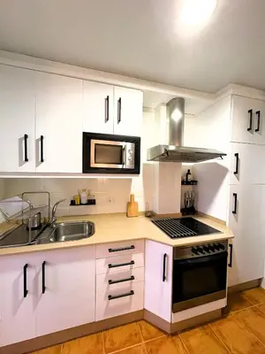 a kitchen with white cabinets and a sink and a microwave at EnBURELA Sol y Playa in Burela de Cabo