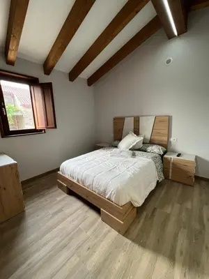 a bedroom with a bed with a wooden headboard and a window at AMC Boente in Arzúa