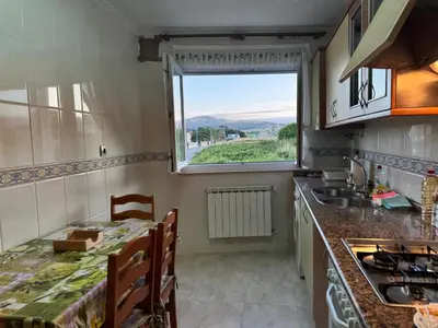a kitchen with a table and a sink and a window at Apartamento Arnela Foz in Foz