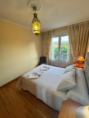a bedroom with a white bed and a chandelier at Apartamento Arnela Foz in Foz