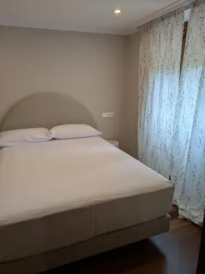 a bedroom with a white bed with a window at Casa Peruxo in Ribadeo