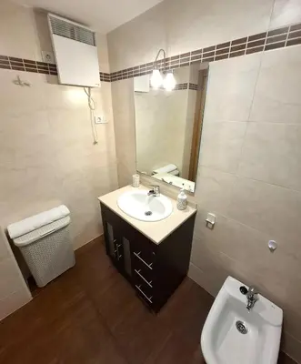 a bathroom with a sink and a toilet and a mirror at Apartamento Playa Foz in Foz