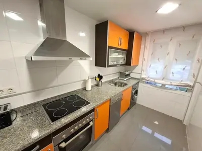 a kitchen with orange and white cabinets and a stove at Apartamento Playa Foz in Foz