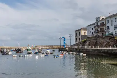 a group of boats floating in a river with buildings at Hotel Puente de los Santos in Tapia de Casariego