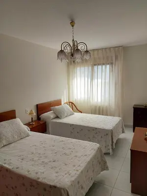 a bedroom with two beds and a chandelier at Alojamiento Sena VUT LE-1254 in Villablino
