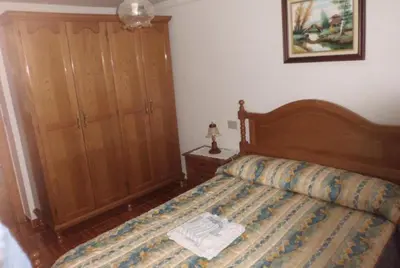 a bedroom with a bed with a wooden headboard and a cabinet at casa jeronimo in Taramundi