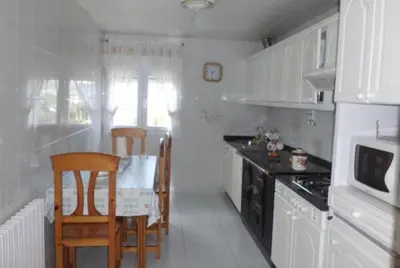 a kitchen with white cabinets and a table and chairs at casa jeronimo in Taramundi