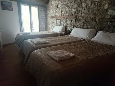 two beds in a room with a stone wall at casa rural San Vicente Borrenes in Borrenes