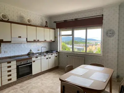 a kitchen with a table and a large window at Piso Mirador de San Cosme in San Cosme de Barreiros