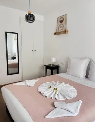 a white bedroom with a pink bed with a flower on it at Eneas I , II in A Pontenova