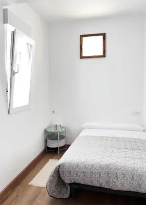 a white bedroom with a bed and a window at Eneas I , II in A Pontenova