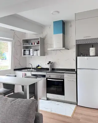 a white kitchen with a white refrigerator and a table at Eneas I , II in A Pontenova