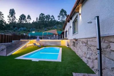 a swimming pool in a yard next to a building at Casa vacacional San Miguel in Maside