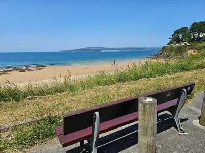 a bench sitting on the side of a beach at Apartamento Playa de Ber in Puentedeume