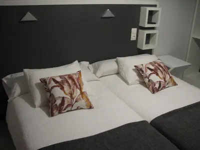 a large white bed with two pillows on it at Hostal Meson do Loyo in Portomarin