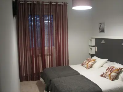 a bedroom with a bed and a window with curtains at Hostal Meson do Loyo in Portomarin