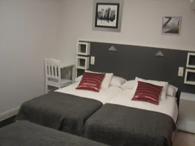 a bedroom with two beds with red pillows at Hostal Meson do Loyo in Portomarin