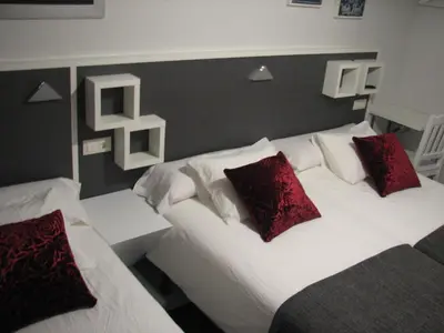 two beds with red pillows in a hotel room at Hostal Meson do Loyo in Portomarin