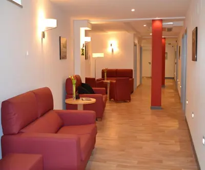a waiting room with couches and tables in a hospital at Hotel Ferramenteiro de Portomarin in Portomarin