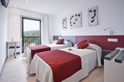 a hotel room with two beds and a window at Hotel Ferramenteiro de Portomarin in Portomarin