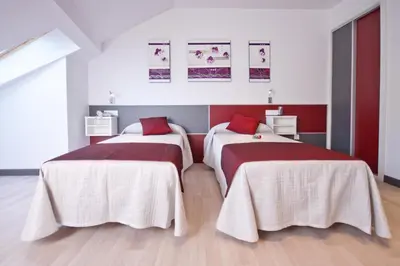 two beds in a room with red and white at Hotel Ferramenteiro de Portomarin in Portomarin
