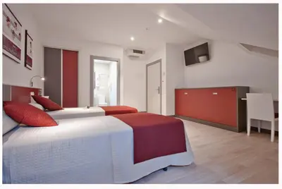 a bedroom with two beds and a television in it at Hotel Ferramenteiro de Portomarin in Portomarin