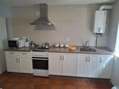 a kitchen with white cabinets and a stove and a sink at As Pitas 4B in Tapia de Casariego
