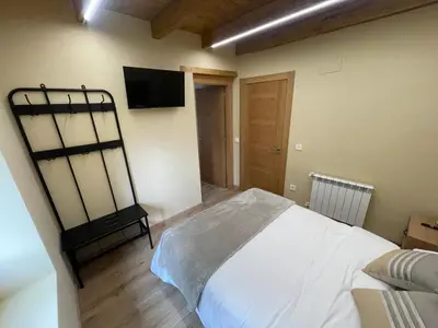 a bedroom with a bed and a flat screen tv at Apartamentos Rurales Casa Carloto