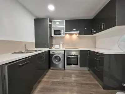 a kitchen with black cabinets and a washing machine at Disfruta de las vistas al Parque de San Lazaro in Ourense