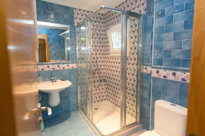 a blue tiled bathroom with a shower and a sink at Casa Melva in Barreiros