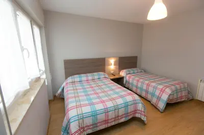 a bedroom with two beds and a table and a window at Casa Melva in Barreiros