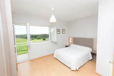 a white bedroom with a bed and a large window at Casa Melva in Barreiros
