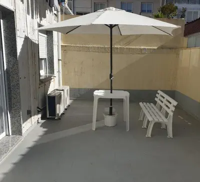 a white table and bench with an umbrella on a building at XELIÑA e in A Estrada