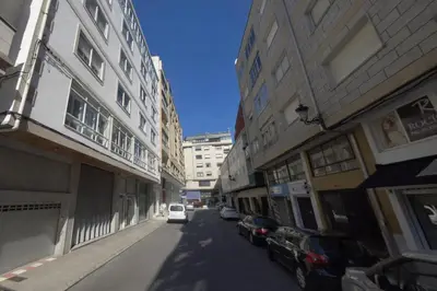 a white car driving down a street next to buildings at XELIÑA e in A Estrada