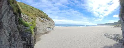 a sandy beach next to the ocean next to a cliff at Vivienda vacacional Casa Rubieiro