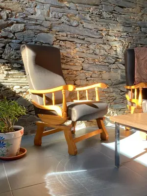 two chairs and a table in front of a stone wall at Ahío San Martín, Apartamentos Rurales Casa de la Villa in San Martín de Oscos