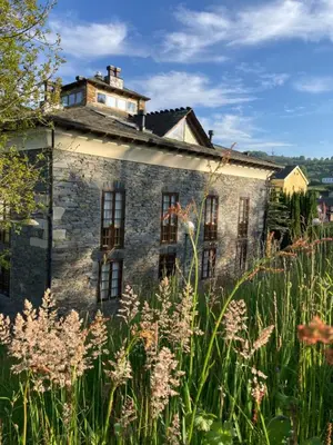 an old stone building in a field of tall grass at Ahío San Martín, Apartamentos Rurales Casa de la Villa in San Martín de Oscos