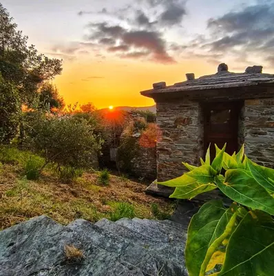 a stone building with the sunset in the background at 39A01 La Casita Olga Casa en plena naturaleza by R2R Consulting in Arrojo