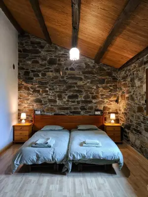 a bedroom with two beds and a stone wall at 39A01 La Casita Olga Casa en plena naturaleza by R2R Consulting in Arrojo