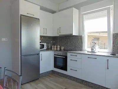 a kitchen with white cabinets and a stainless steel refrigerator at Casa Esperanza 8 huéspedes