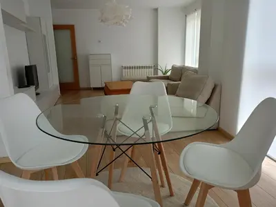 a glass table and four white chairs in a living room at Rúa Mariñeiro in Burela de Cabo